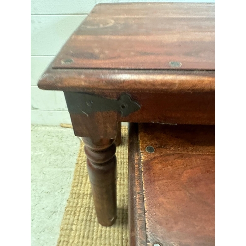 23 - A nest of three hardwood tables with black metal studded detail