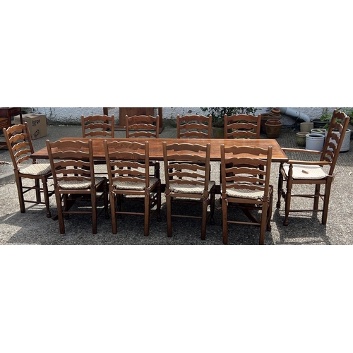66 - A large oak dining table with ten ladder back chairs (H73cm W243cm D90cm)