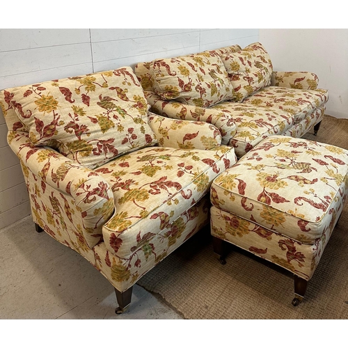 87 - A three seater sofa with matching arm chair and footstool by Edward Ferrell upholstered in a scrolli... 