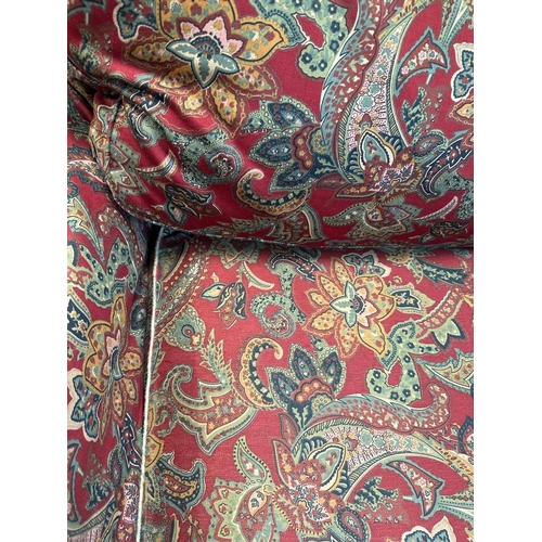 90 - A red paisley upholstered corner sofa