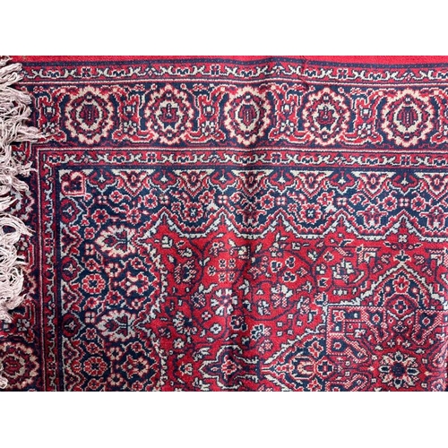 176 - A small red ground rug with geometric boarder and central shield 106cm x 67cm