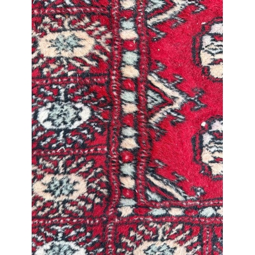 180 - A red ground rug with geometric border 64cm x 106cm