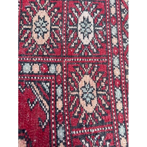 180 - A red ground rug with geometric border 64cm x 106cm