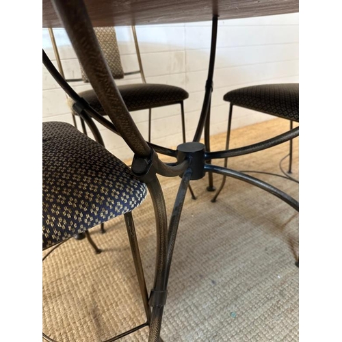 22 - A wrought iron circular dining table and chairs, the table with a wooden top and the chairs upholste... 