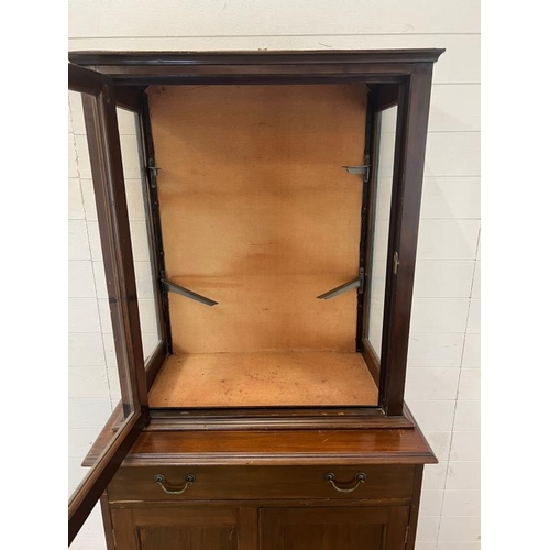 26 - A glazed display unit upon a cabinet base with panelled doors (H174cm W81cm D50cm)