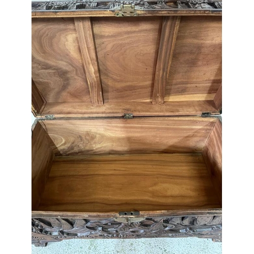 29 - A Chinese ornately carved camphor wood chest with brass fittings and featuring a desert scape scene ... 