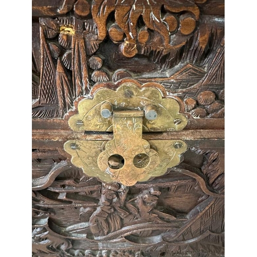 29 - A Chinese ornately carved camphor wood chest with brass fittings and featuring a desert scape scene ... 