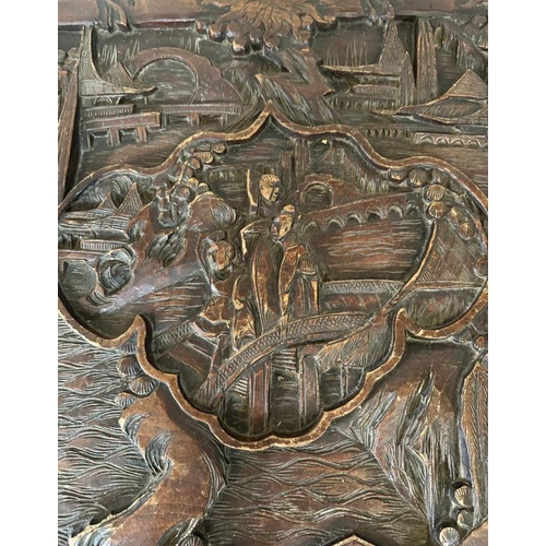 29 - A Chinese ornately carved camphor wood chest with brass fittings and featuring a desert scape scene ... 