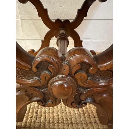 79 - A walnut framed foot stool on an ornately carved X frame with turned stretcher