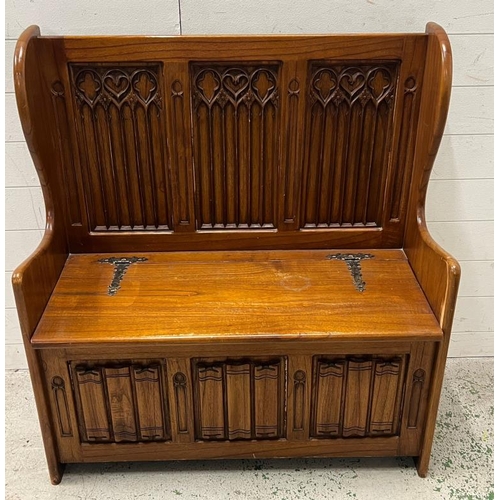 83 - A Gothic style monks bench with hinged lid and linen fold detail (H103cm W94cm D41cm)