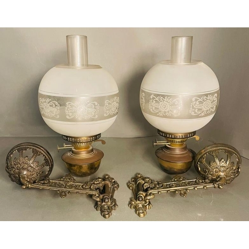 235 - A Pair of bras and glass wall oil lamps on ornate arm.