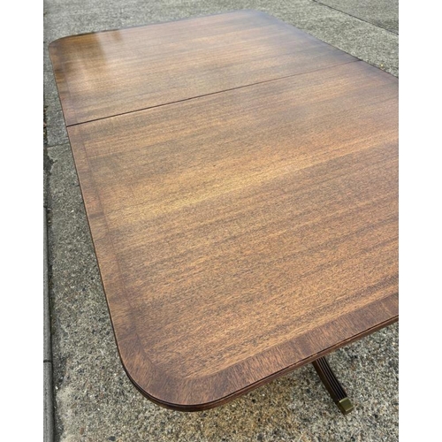 46 - A Regency style mahogany dining table on splayed legs sitting on brass feet with an extra leaf (H70c... 