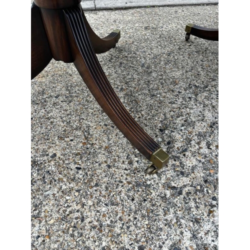 46 - A Regency style mahogany dining table on splayed legs sitting on brass feet with an extra leaf (H70c... 