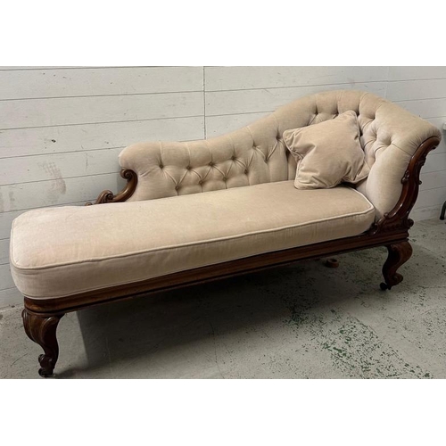 100 - A mahogany frame button backed chaise long upholstered in an ivory fabric and on carved legs and cas... 