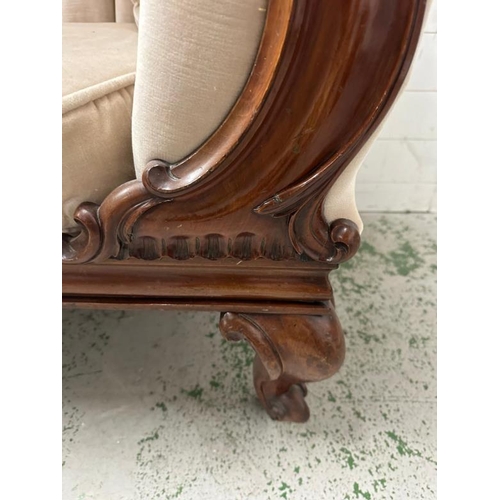 100 - A mahogany frame button backed chaise long upholstered in an ivory fabric and on carved legs and cas... 