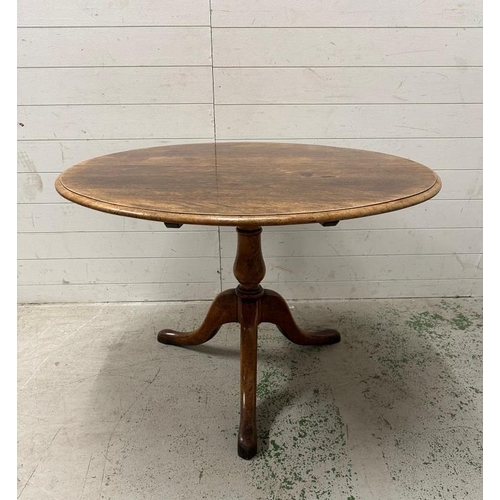 101 - An oak tilt top breakfast table on turned central support on splayed legs (H73cm Dia102cm)