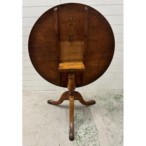 101 - An oak tilt top breakfast table on turned central support on splayed legs (H73cm Dia102cm)