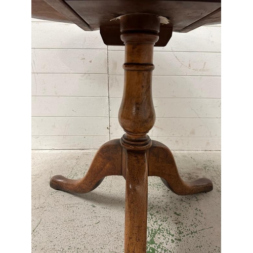 101 - An oak tilt top breakfast table on turned central support on splayed legs (H73cm Dia102cm)