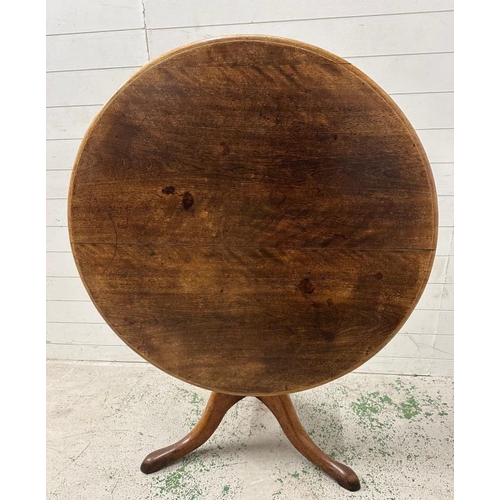 101 - An oak tilt top breakfast table on turned central support on splayed legs (H73cm Dia102cm)