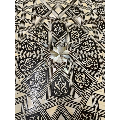 114 - A Moroccan style low pedestal table on splayed legs with geometrical mother of pearl and ebony inlay... 