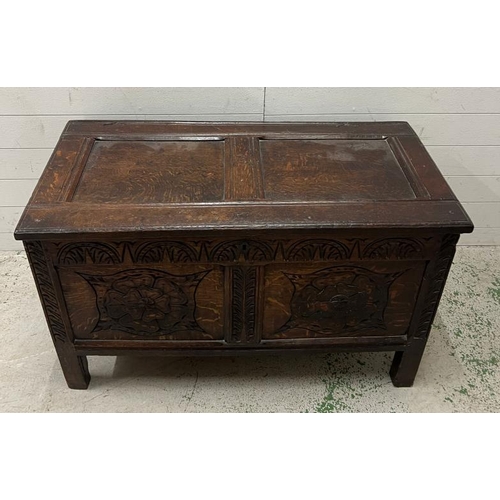 14 - An oak coffer the front carved with Tudor rose roundels (H64cm W107cm D53cm)