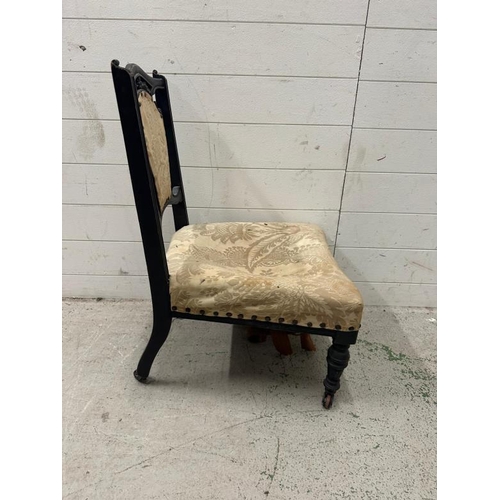 50 - An ebonised and carved bedroom chair with cream floral upholstery