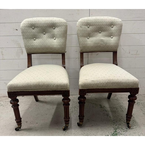 57 - A pair of mahogany aesthetic movement hall chairs on castors in a pale green upholstery