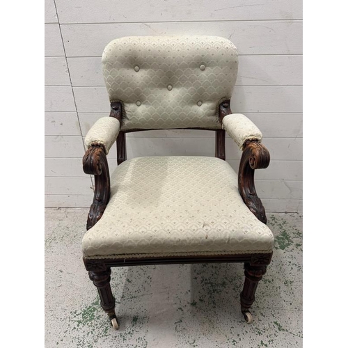 58 - A mahogany carved open arm chair on castors in a pale green upholstery