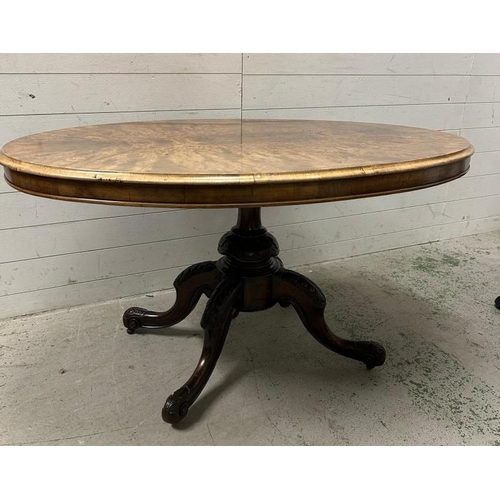 83 - An oval burr walnut topped centre table on ornately carved out swept mahogany legs ending on scrolli... 