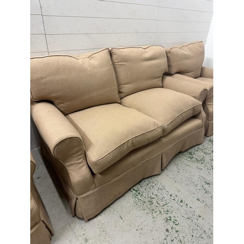 84 - A three seater sofa and two matching arm chairs upholstered in a beige fabric