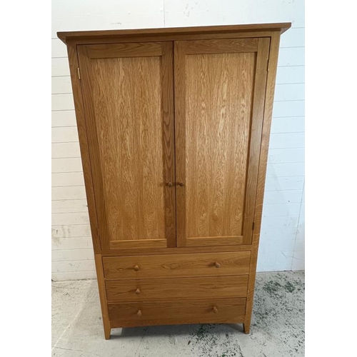 89 - Double wardrobe in light oak, the double doors open to hanging rail and three drawers below, possibl... 