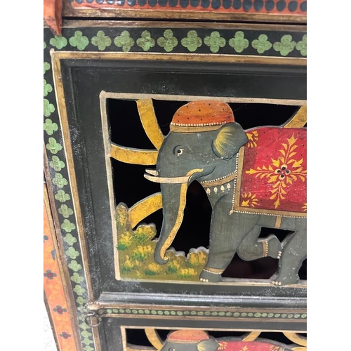 102 - An Indian folk art painted cupboard, the doors featuring elephants in traditional costume and the si... 