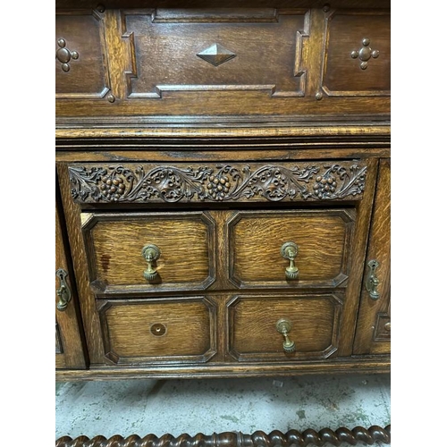 172 - An oak Jacobean style heavily carved court cupboard with three central drawers flanked by cupboards ... 