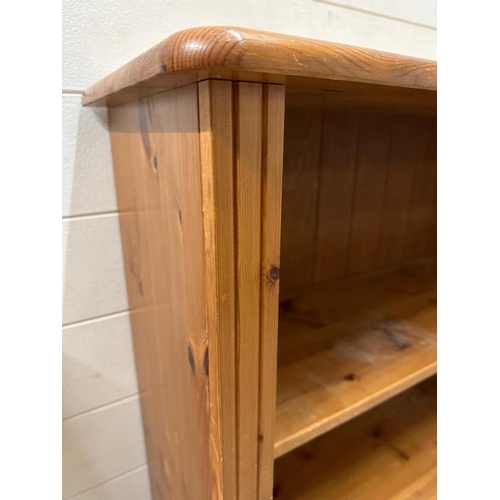 187 - A pine three shelf bookcase on bun feet (H125cm W87cm D29cm)