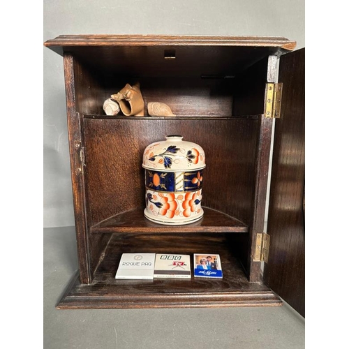 385 - A Victorian carved oak smokers cabinet, bevel glazed and complete with ceramic tobacco jar and clay ... 