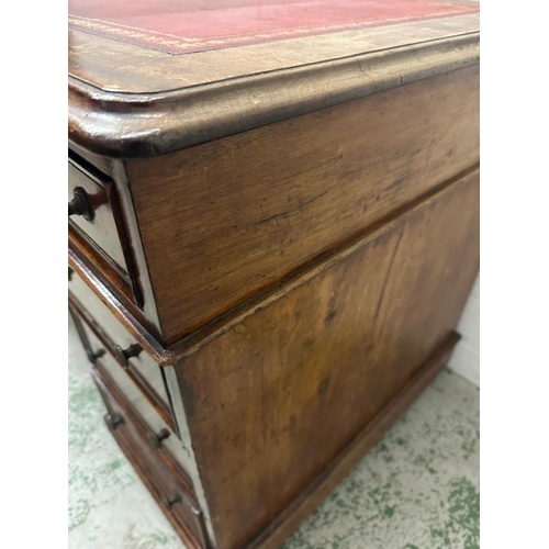 55 - A red leather topped pedestal desk with a central long drawer flanked by four drawers on either side... 