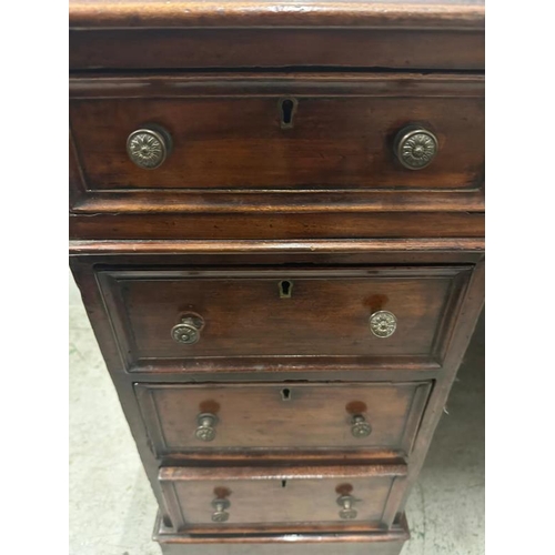 55 - A red leather topped pedestal desk with a central long drawer flanked by four drawers on either side... 