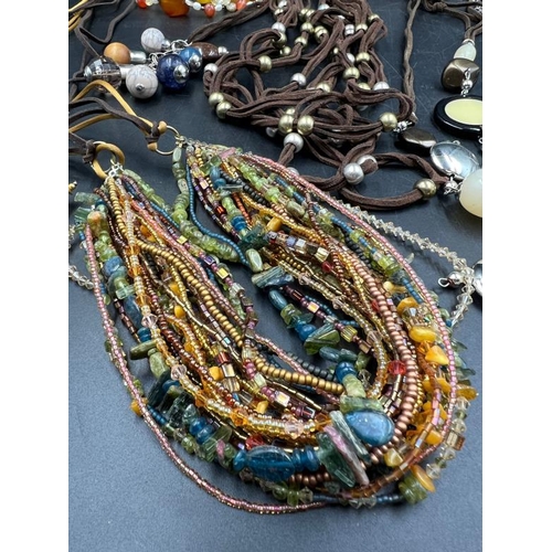 707 - A collection of Earth tones costume jewellery, multi layer row beaded necklaces, charm bracelets etc