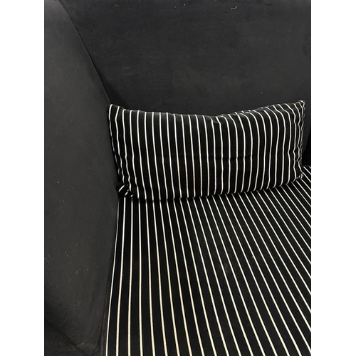 148 - A large black high backed sofa with black and white striped cushions (H105cm W240cm D108cm)