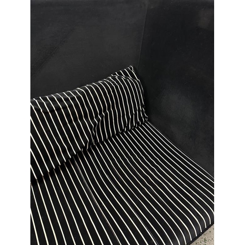 148 - A large black high backed sofa with black and white striped cushions (H105cm W240cm D108cm)