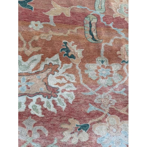 199 - A large wool rug, red grounds  with a floral pattern and floral geometric boarder (410cm x 307cm)