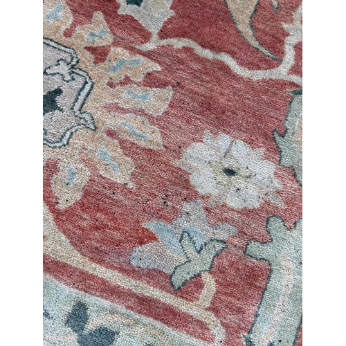 199 - A large wool rug, red grounds  with a floral pattern and floral geometric boarder (410cm x 307cm)