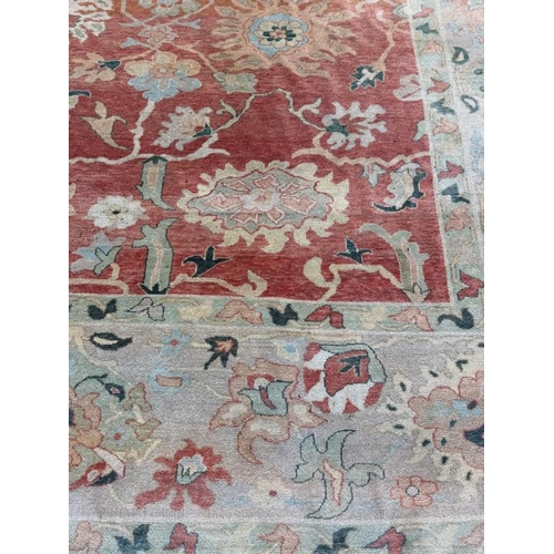 199 - A large wool rug, red grounds  with a floral pattern and floral geometric boarder (410cm x 307cm)