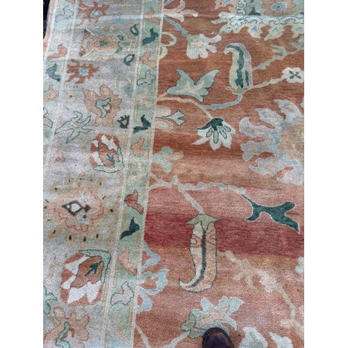 199 - A large wool rug, red grounds  with a floral pattern and floral geometric boarder (410cm x 307cm)