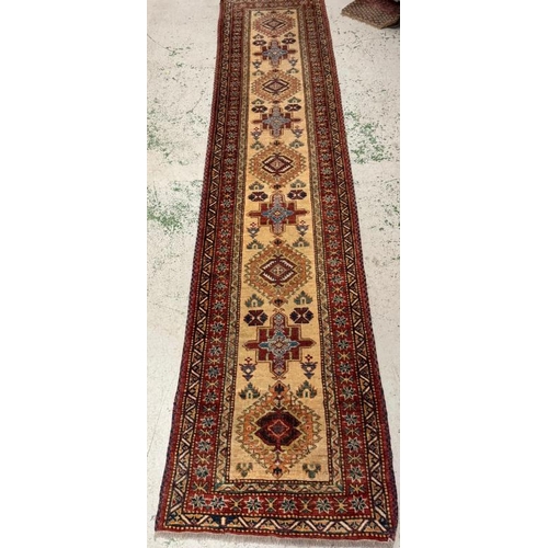 202 - A wool runner, red grounds and with a geometric border (301cm x 72cm)