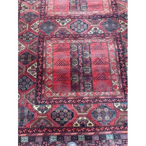 209 - A wool rug, red grounds with a geometric boarder 260cm x 170cm