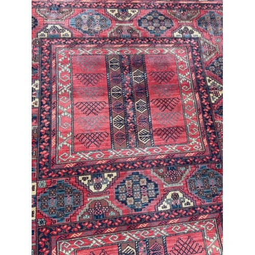 209 - A wool rug, red grounds with a geometric boarder 260cm x 170cm