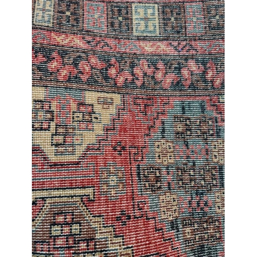 209 - A wool rug, red grounds with a geometric boarder 260cm x 170cm