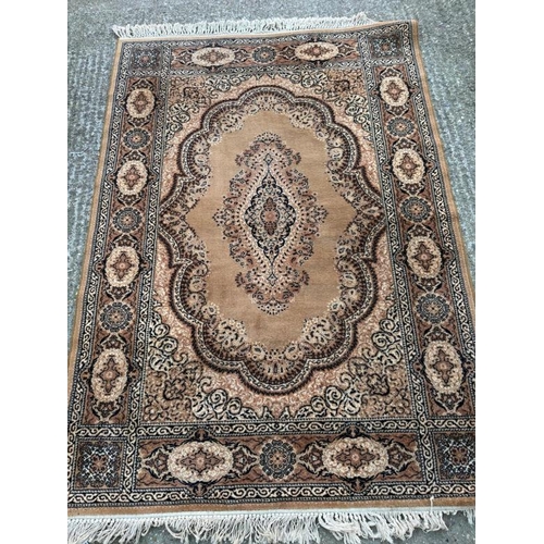 210 - A wool rug, brown grounds with central medallion and geometric boarder 200cm x 140cm