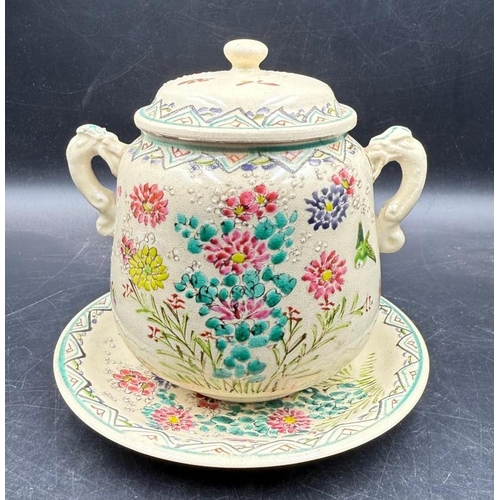 290 - A lidded jar on matching saucer with accent tassel handles and hand painted floral pattern